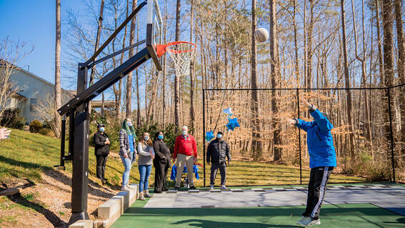 Luke shooting a basketball with family and friends watching