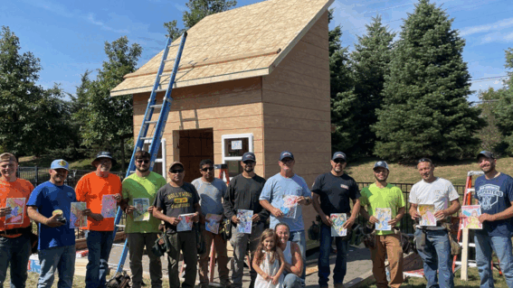 Tessa and playhouse building crew holding their drawings made by Tessa