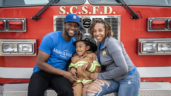 Jayce and his parents sitting in front of the firetruck