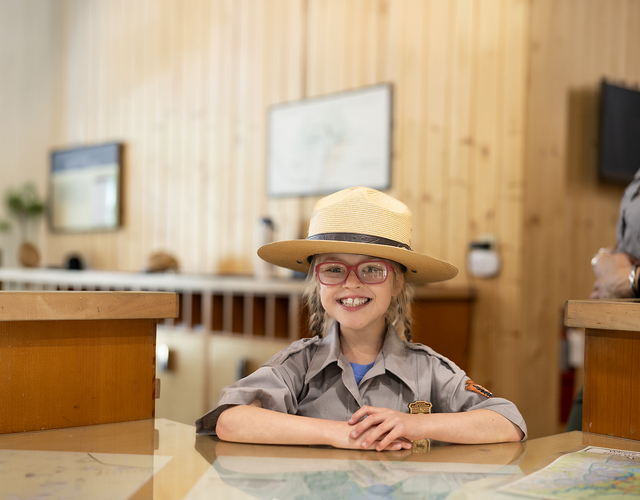 Wish kid Sammy sitting at a desk wearing a National Park Service ranger uniform