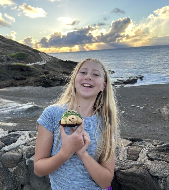 Wish kid Nora smiling brightly standing on a black sand beach