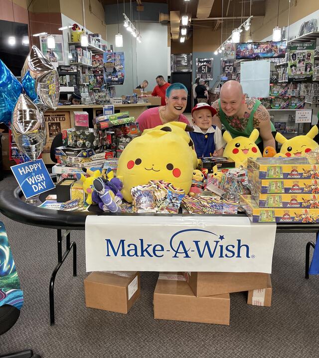 Arthur posing behind a table full of Pokemon cards with his mom and stepdad
