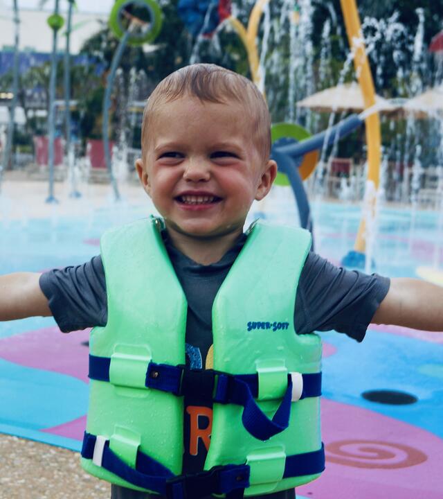 Knox at a waterpark in his life jacket with his arms stretched out