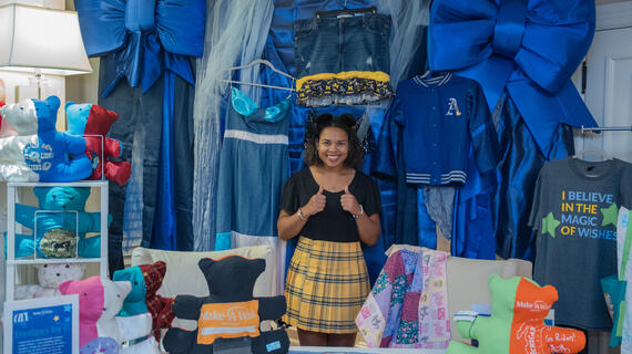 a wish alum running her own pop-up booth. She is selling her own designs that Make-A-Wish inspired clothing items.