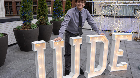 Jude standing in front his giant light up letters spelling his name - JUDE