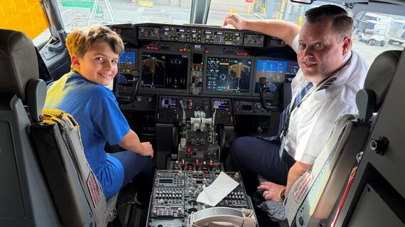 Wish child and airline pilot in the front seat of an airplane.