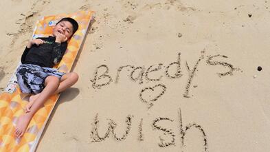 Boy laying on a surfboard on the beach 