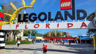 Wish kid Rowan smiling with excitement posing under the entrance sign for Legoland