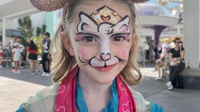 A cute young girl wearing Mickey ears at Disney.