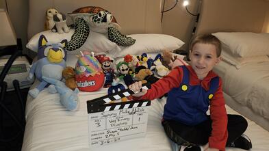 A young boy sitting on a bed with a bunch of stuffed animals
