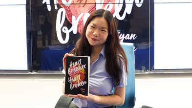 Wish kid Ziyan smiles, posing with her book during her wish celebration.