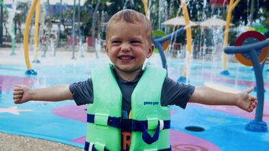 Knox at a waterpark in his life jacket with his arms stretched out
