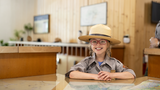 Wish kid Sammy sitting at a desk wearing a National Park Service ranger uniform