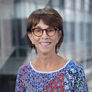Woman smiling. She has short brown hair and is wearing glasses.