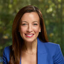 Kim Elenez smiling and wearing a white shirt with blue blazer