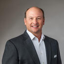 Russ Webb smiling and wearing a white shirt with grey suit jacket