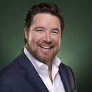Ryan Chismark smiling and wearing a white shirt with navy suit jacket