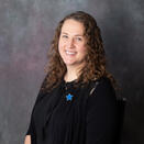 Headshot of Emma in a black shirt and blue star pin