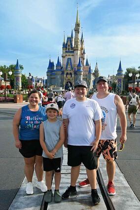Jaxon and his family posing in front of the Disney World Castle