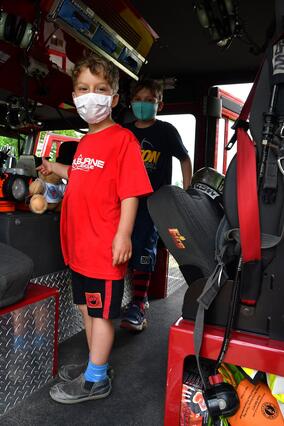 two children look out from the back of a fire truck