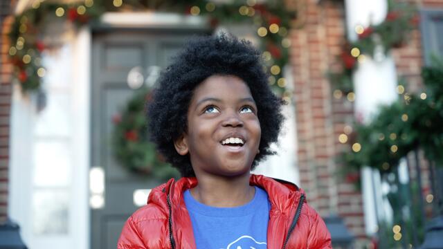 Austin is smiling looking up in front of the Home Alone house
